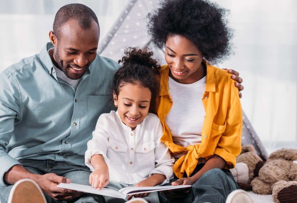 happy african american daughter reading for parents at home