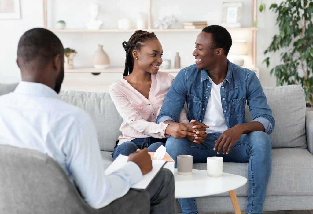Successful Couples Therapy. Reconciled black spouses embracing at therapist office